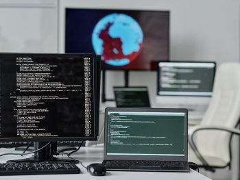 Close-up of computer monitor with codes on the screen standing on table of developer